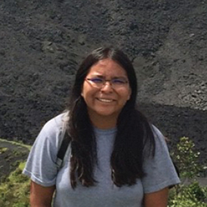 student with glasses in front of a volcano